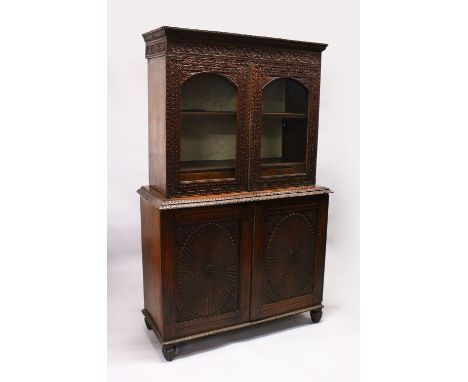 A GOOD 19TH CENTURY ANGLO INDIAN PADAUK WOOD CUPBOARD BOOKCASE, with floral carved cornice, a pair of arched glazed doors enc