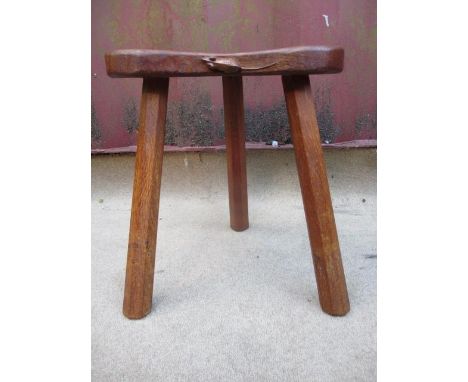 A Robert Thompson Mouseman carved oak stool with a kidney shaped, dished top, raised on octagonal, tapered legs, 14" h x 12" 