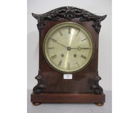 A Victorian mahogany cased mantle clock having an 8" silvered dial and Roman numerals in a carved, floral and scrolled case, 
