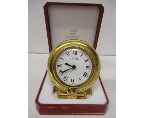 A Cartier quartz gilt metal cased, modern bedside clock having a circular case, white enamel dial and black Roman numerals, 3