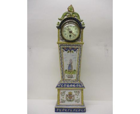 An early 20th century faience mantle clock in the form of a long case clock, having a pierced, scrolled top and all over pain