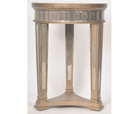 A contemporary Hollywood Regency mirrored lamp / side table having a circular mirrored top with mirrored panels to the frieze