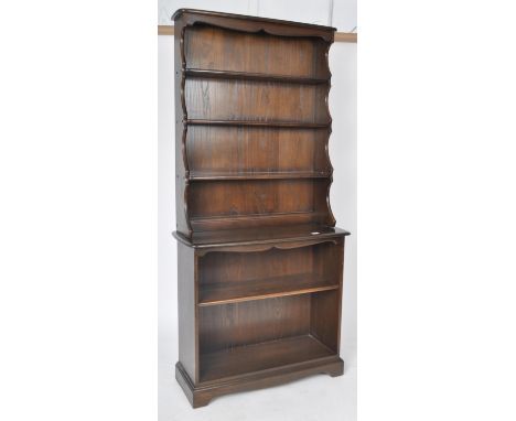 Ercol - A retro 20th Century elm Windsor two pieces bookcase cabinet having a three shelf waterfall top over a single shelf o