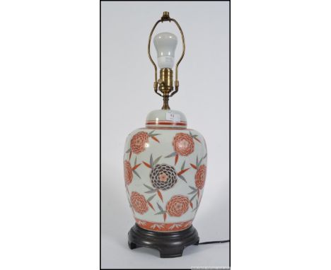 A Japanese ceramic chrysanthemum ginger jar converted into a lamp.  Brass fittings along with wooden base plinth stand. Measu