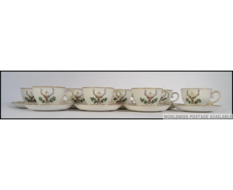 A set of eight Austrian hand painted bone China cups and saucers, having a stags head bellow a golden cross raised above cros