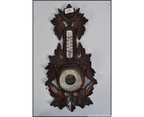 A carved Black Forest aneroid barometer with central dial and milk glass thermometer above. Measures: 45cm x 23cm.