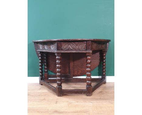 A 17th Century oak Credence Table with dropleaf supported on a gateleg, fitted carved frieze drawer and raised on bobbin turn