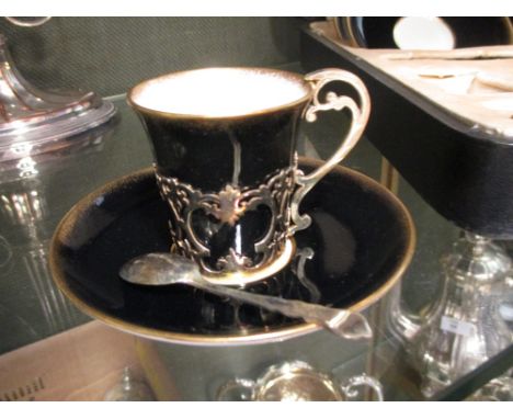 A cased set of Aynsley coffee cups and saucers with gilt cup holders  Chip to the rim of one coffee can. Hairline crack on a 