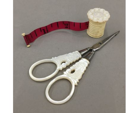 A Victorian turned bone and mother-of-pearl measuring tape, together with a pair of mother-of-pearl handled scissors en-suite