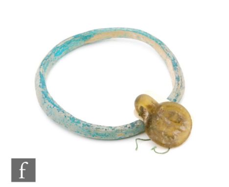 Roman 2nd to 4th Century AD - An olive glass pendant impressed with a standing lion and sea green glass bangle, diameter 6cm 