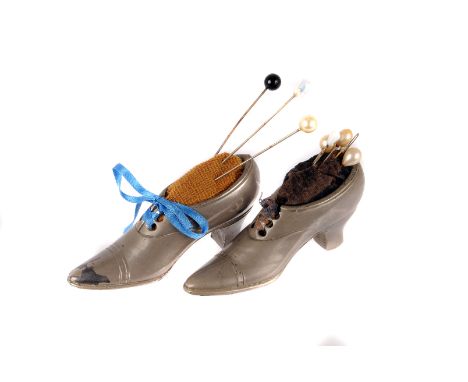 A pair of vintage pewter shoe pin cushions, modelled as a lady's shoe with inset pad and several pins and three hat pins 