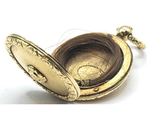 Yellow metal mourning locket, probably Victorian, with engine-turned and flowerhead decoration, enclosing a lock of hair, len
