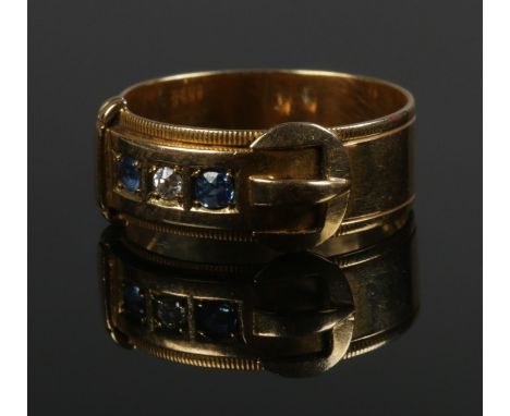 An 18ct gold three stone diamond and sapphire buckle ring. Size R. 5.11g.  