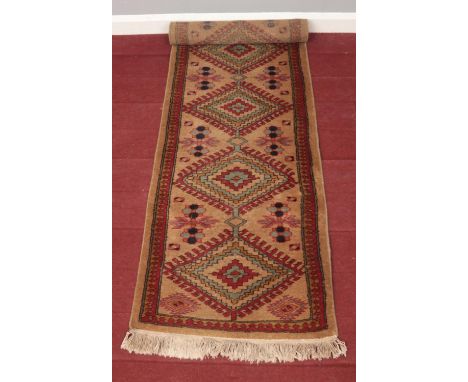 A light brown ground carpet runner with Aztec design. L: 182cm, W:60cm.  Condition good. No holes.