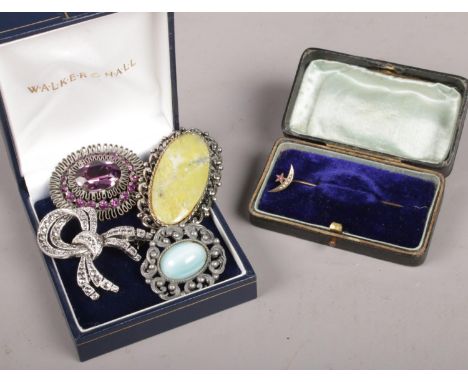 A yellow metal and seed pearl crescent stick pin along with four costume jewellery brooches.  