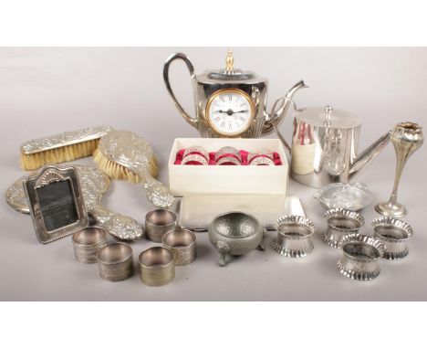 A box of metalwares. Including brush set, teapot, napkin rings, teapot clock, etc.  