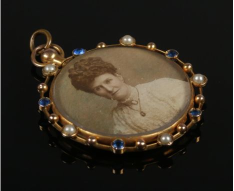 A 9ct gold double sided photograph locket/pendant. Set with seed pearls and blue stones. Each side with a portrait photograph