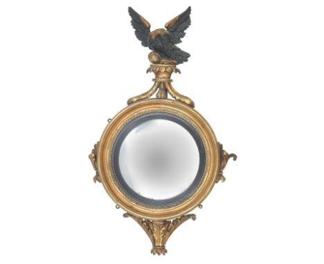 A giltwood and gesso convex wall mirrorWith an ebonised eagle finial and reeded slip, 55cm wide, 90cm high (21 1/2in wide, 35