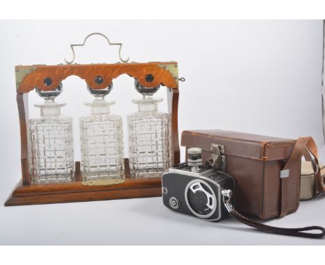 An Edwardian oak three-bottle tantalus, width 37cm, a pair of brass faced bellows, stoneware flagon, T. & E. Taylor, Bradford