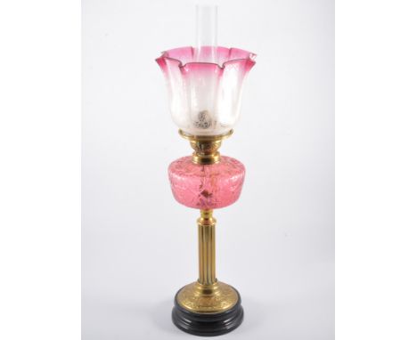 A Victorian brass oil lamp, cranberry tinted moulded glass reservoir, shade and chimney, 71cm, a brass candlestick peg lamp c