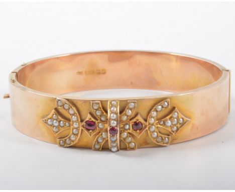 A 9 carat rose gold half hinged bangle, 14mm wide with raised decoration to front set with fifty-two seed pearls and three un