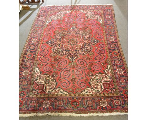 Persian carpet, central floral medallion on a crimson ground, with scrolling design enclosed by ivory floral spandrels and re