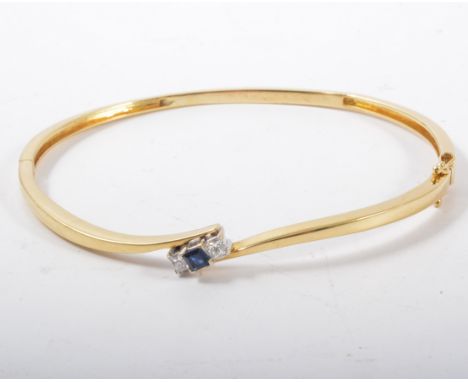 A contemporary sapphire and diamond bangle, a square cut sapphire with a princess cut diamond to each set to the centre of an