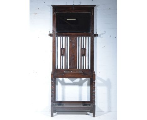 1940s oak hall stand, rectangular bevelled plate, surrounded by five hooks, above an umbrella/stick rack with hinged compartm