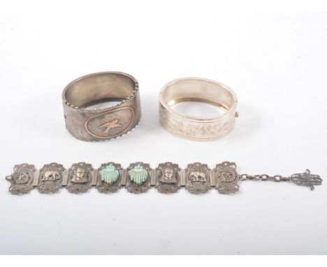 Two silver coloured half hinged bangles and a bracelet, one 30mm wide bangle having a gilt bird to front and beaded border ma