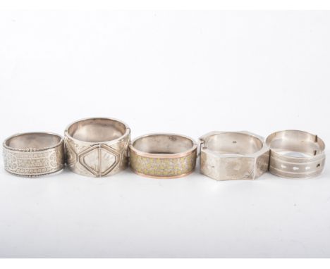 A hallmarked silver bangle and four other white metal bangles, the 25mm wide belt design engine turned bangle hallmarked Ches