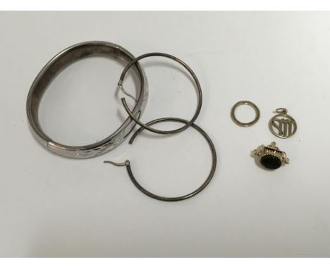 A yellow metal spinning fob, sterling silver bangle, with additional jewellery items.