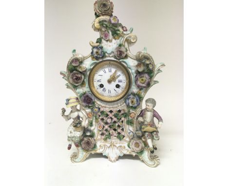 A quality late 19th century German porcelain clock the case encrusted with raised flowers with two seated figures holding bas