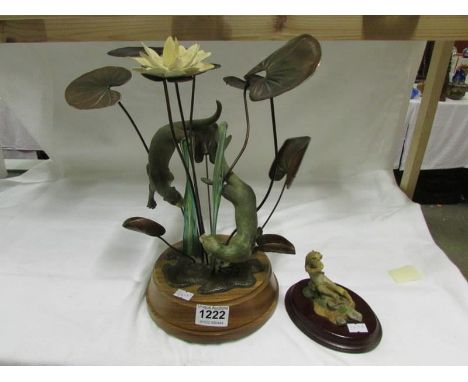 A figure group of otters playing round water lilies and a small otter figure