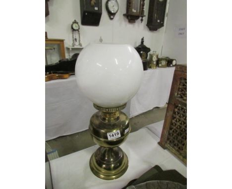 A brass oil lamp with shade but missing chimney