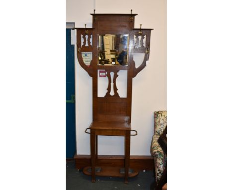 An Arts and Crafts oak hall stand, early 20th century, with various hooks and mirror above compartment and stick stands, 210c
