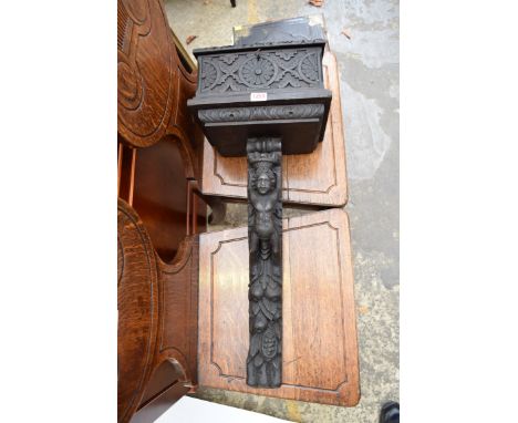 An old carved oak church collection box, the bracket support carved with a cherub. 