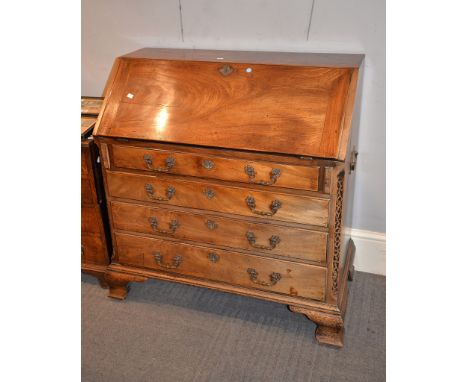 A George III mahogany bureau, the sloping flap enclosing an arrangement of drawers and pigeonholes and a concealed well, abov