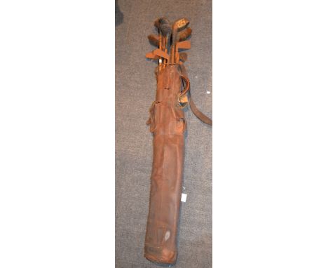 A quantity of vintage wooden shafted golf clubs, in a leather bag  
