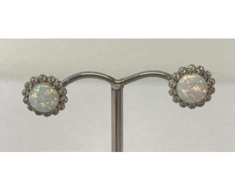 A pair of opal and cubic zirconia stud earrings marked 925.Central round opal surrounded by 14 small cubic zirconia stones.