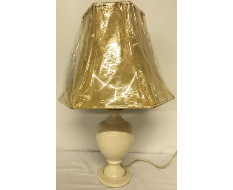 A cream crackle glaze table lamp with gold bell shape shade.