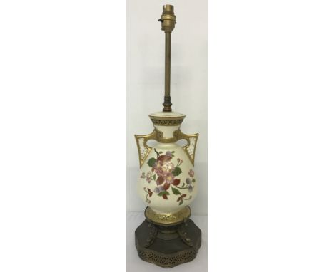 Hand decorated and gilded ceramic table lamp with pierced work handles.Surmounted on a decorative metal base with dolphin ped