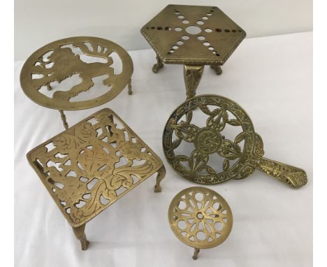 A collection of 5 vintage brass trivets.To include a Victorian stove hanging trivet and a heavy hexagonal shaped trivet raise