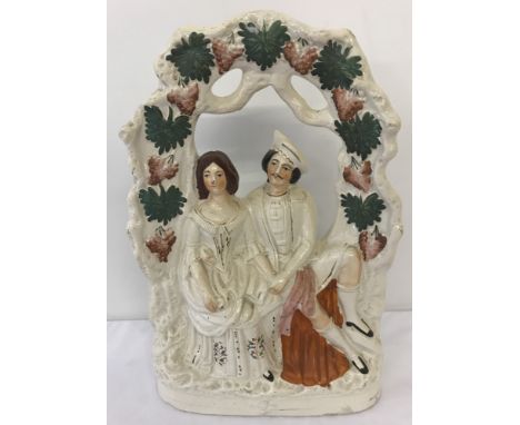 A large Staffordshire ceramic  figurine of a courting couple sat beneath a bough of grape vines.Approx. 36cm tall x 23cm wide