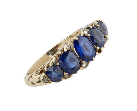 A late Victorian sapphire set ring  claw set with five graduated oval and cushion cut sapphires, diamond chip detail, the gal