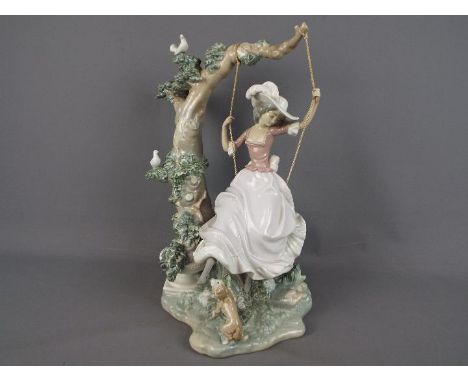 Lladro - A large Lladro figure group depicting a girl on a swing, suspended from a tree with perching birds and a playful can
