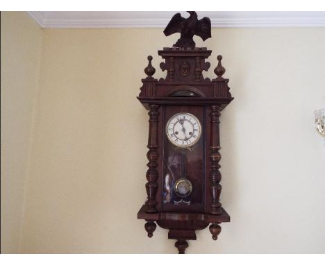 A Vienna style wall clock, opening glazed door flanked by turned columns, the case surmounted by a stepped pediment having tu