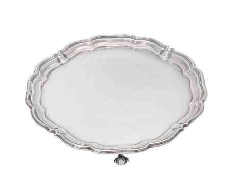 A silver shaped circular salver by Harrison Brothers &amp; Howson, Sheffield 1944, with a raised moulded rim and on four scro