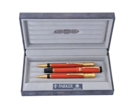 Parker, Duofold, an orange ball point pen, roller ball pen and propelling pencil, the roller ball pen cap with gilt arrow cli