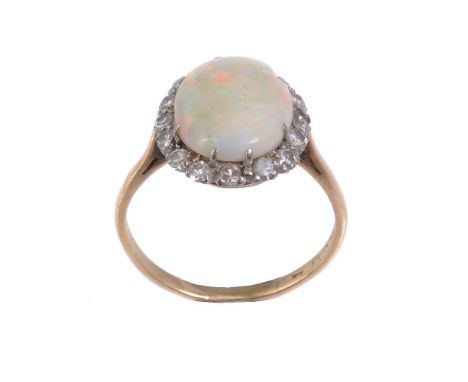 An opal and diamond ring, the central oval opal claw set within a surround of eight cut diamonds, approximately 0.32 carats t