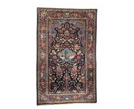 A Persian Kashan rug, a pictorial central lotus cartouche depicting a desert oasis reserved against a foliate decorated dark 